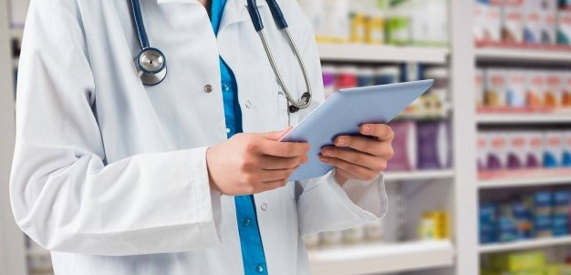 A pharmacist using a tablet on the drug store