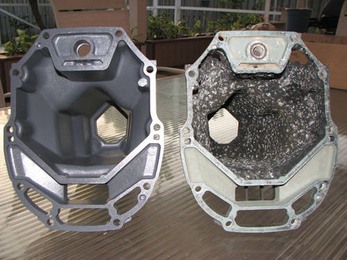 Two outboard engines sitting side by side, one corroded and one looking clean.