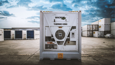 A Thermo King® Magnum® Plus sits by itself in a container storage area at a shipping dock.