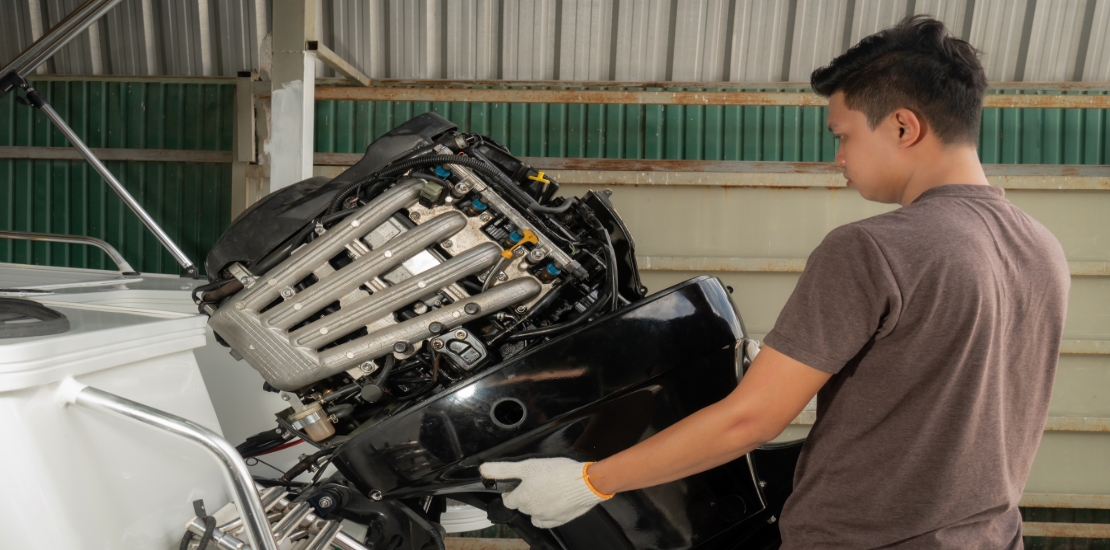 A man is disassembling an outboard motor for maintenance.